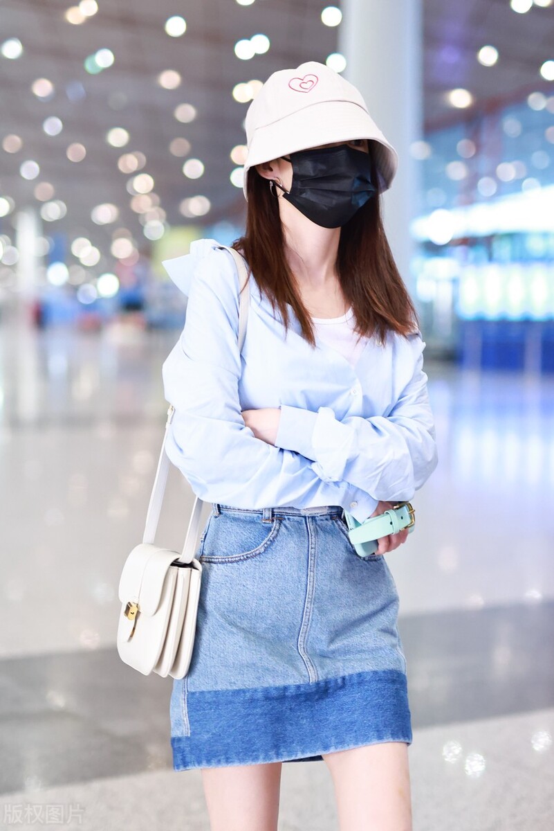 Li Qin wears a blue shirt with a denim skirt and white shoes on her ...